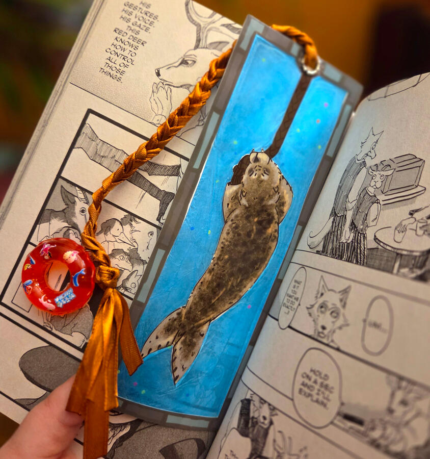 Seal Tug-of-War bookmark; translucency done with tissue paper. Designed, printed, Hand cut, glued, hot laminated and assembled in-house